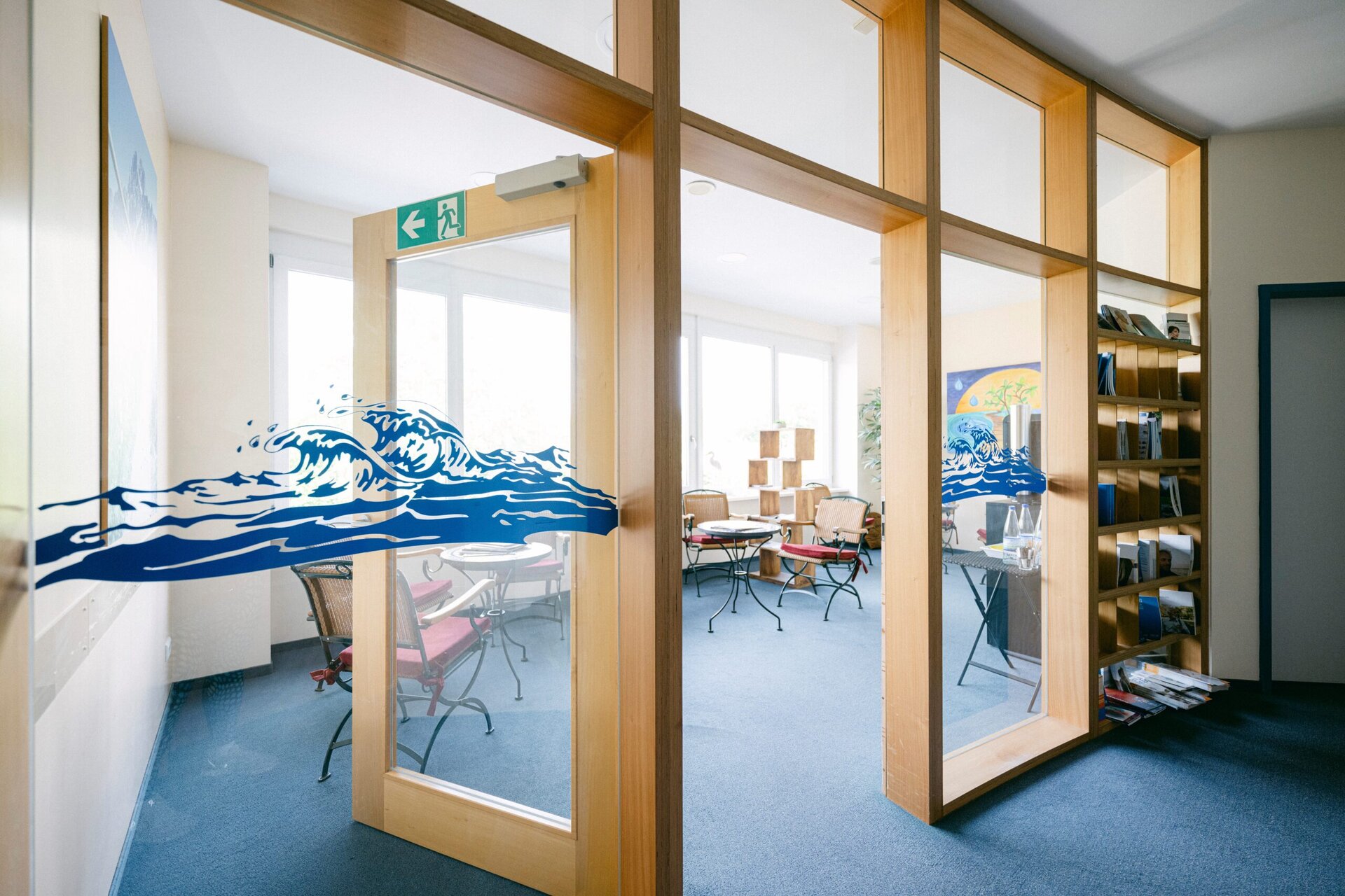 Das Wartezimmer der Praxis ist durch eine Glastüre zu sehen.