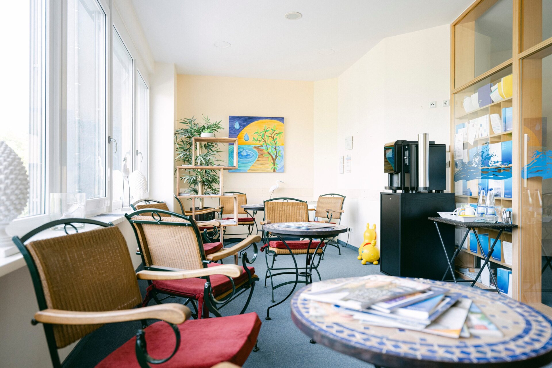 Helles Wartezimmer im Onkologischen Zentrum Passau mit bequemen Sitzgelegenheiten, kunstvoller Dekoration und Informationsmaterial.