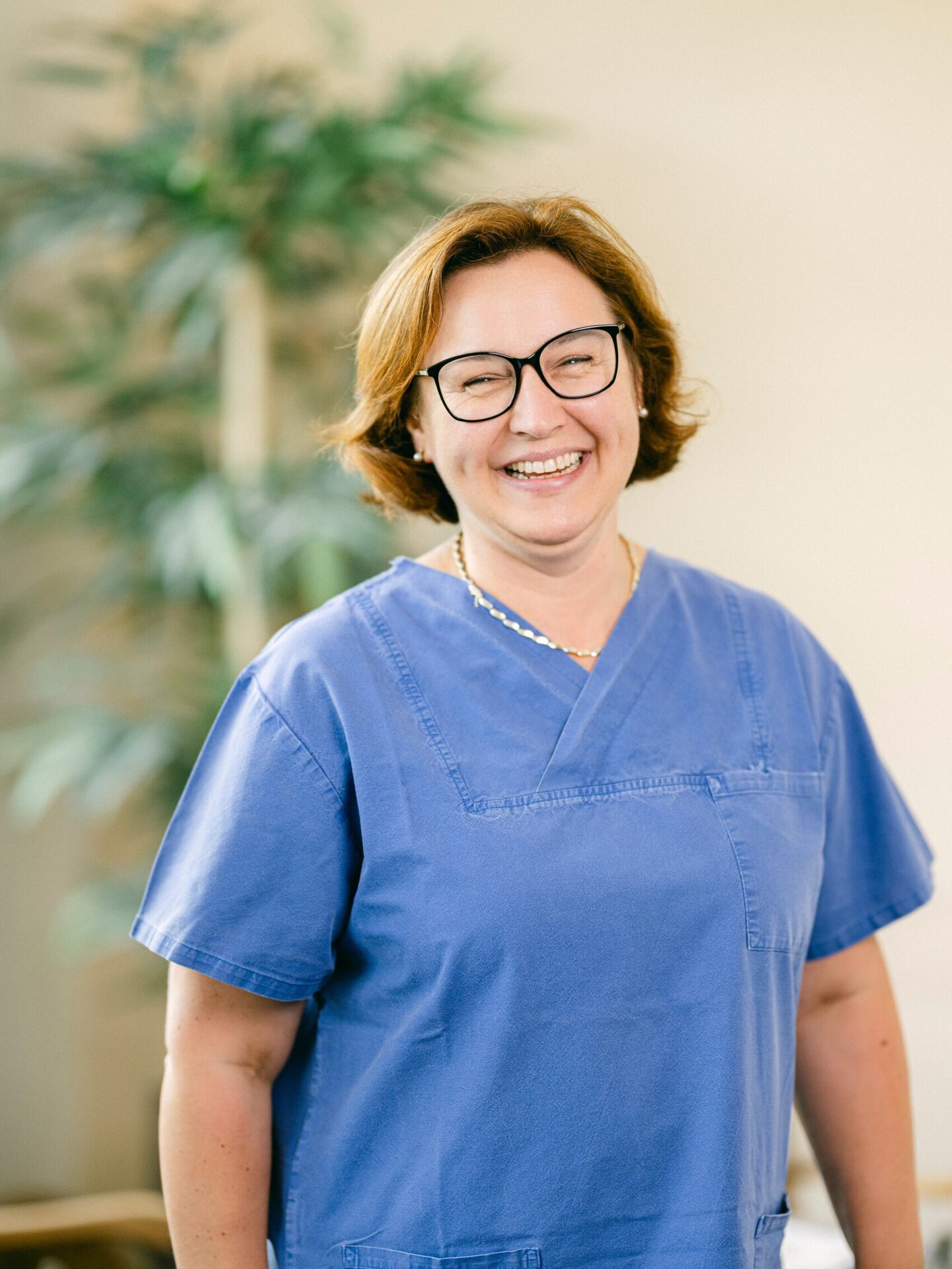 Pflegekraft im Onkologischen Zentrum Passau, mit freundlichem Lächeln, in blauer Pflegeuniform.