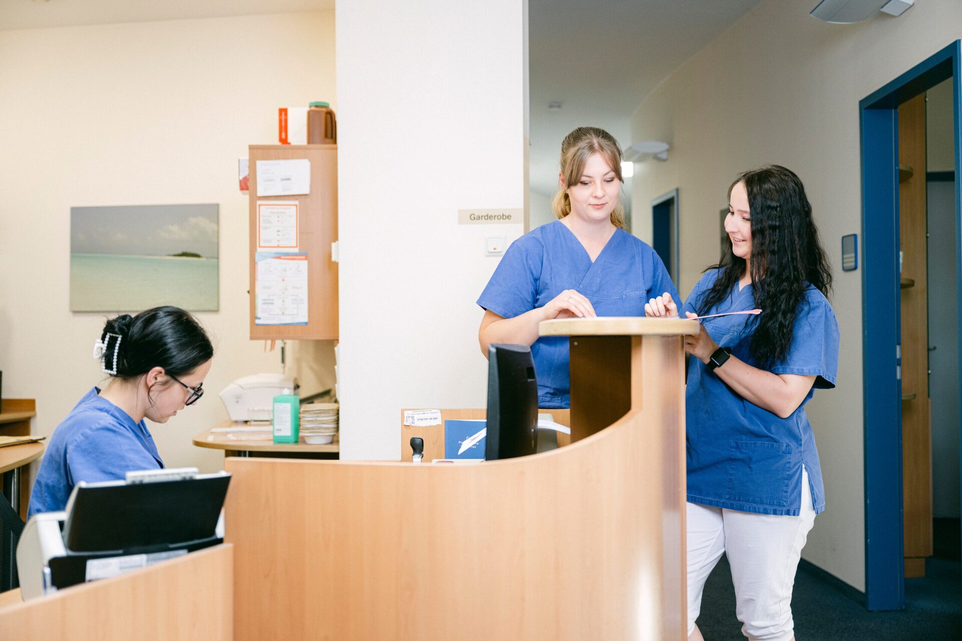 3 MFAs arbeiten am Empfang der Praxis miteinander.