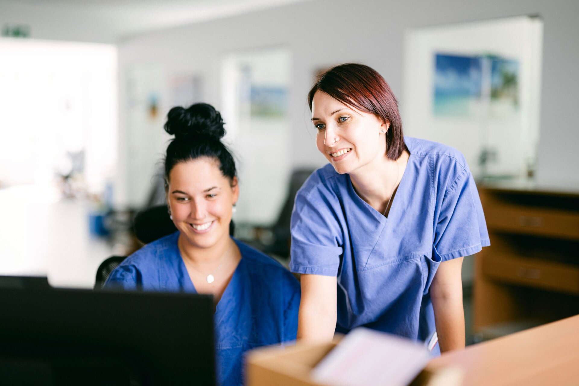 2 MFAs prüfen etwas auf einem Bildschirm.